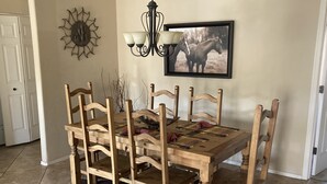 A dining table with six wooden chairs, a chandelier, a framed horse picture, and a sun decoration on the wall. - 2 bed 2 bath condo (Fountain Hills)