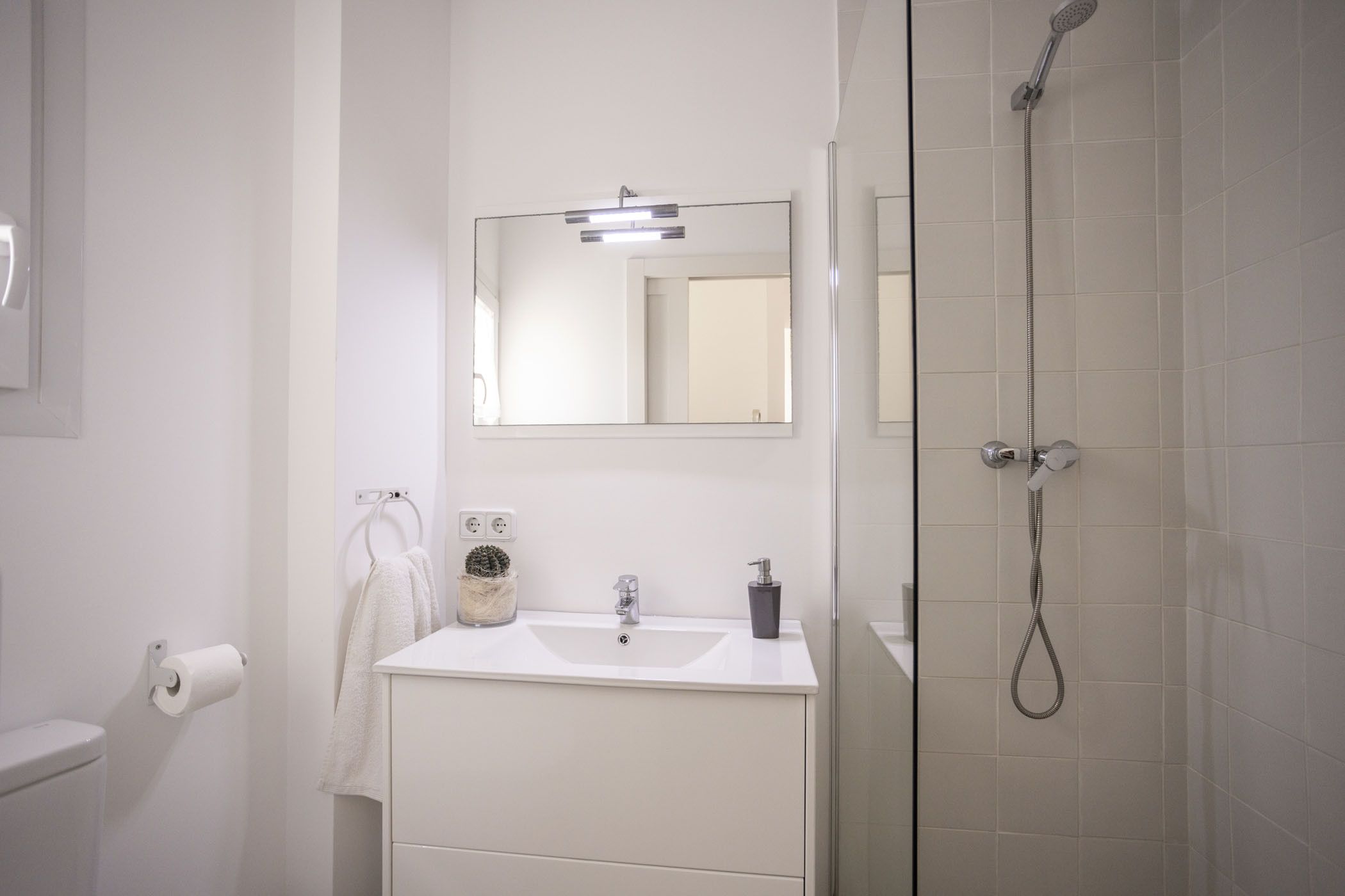 A bathroom with a white sink, a mirror, a shower, and a toilet.