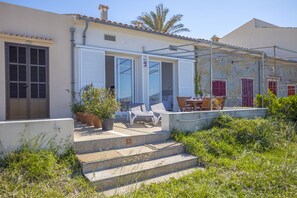Ein Haus mit Terrasse, Sitzgelegenheiten im Freien und einer Steinmauer.