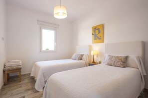 Ein Hotelzimmer mit zwei Betten, einem Fenster, einer Lampe und einem kleinen Tisch mit Handtüchern.