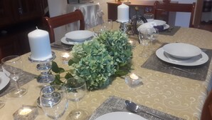 A dining table set with plates, glasses, and candles, surrounded by chairs.