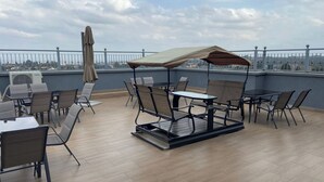 A rooftop terrace with outdoor seating, including tables and chairs, and a covered area with an umbrella. - Neema Executive Suites Near Junction Mall 5A (Nairobi)