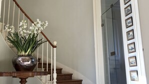 A staircase with a wooden handrail and a white wall with framed pictures.