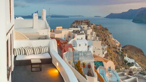 A seaside hotel with a balcony overlooking a coastal town and the sea. - Sophia Privilege (Santorini)