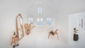 A bright, white room with a large mirror, a wooden chair, and a potted plant. - Sophia Privilege (Santorini)