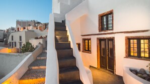 A white building with a staircase leading to a door, surrounded by other buildings. - Sophia Privilege (Santorini)