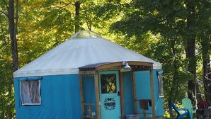A small, single-story yurt with a porch, a welcome sign, and a butterfly decoration.