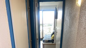 Un pasillo estrecho con adornos azules que conduce a una habitación con cama y ventana.