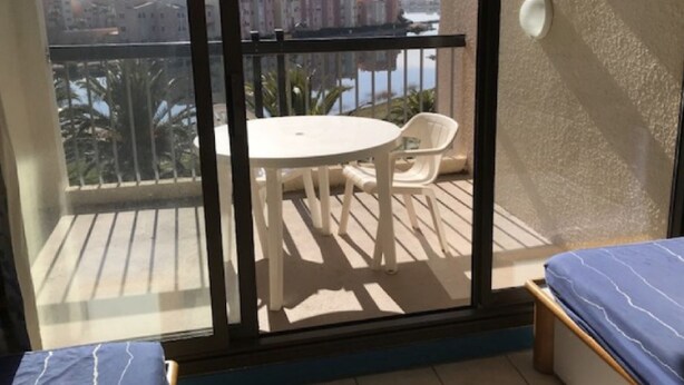 Un balcón con mesa y sillas, una cama y vistas a edificios y al agua.