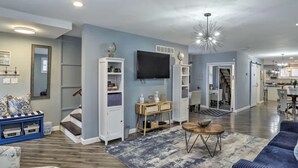 A spacious living room with a flat-screen TV, built-in shelving, and a staircase leading to another level.