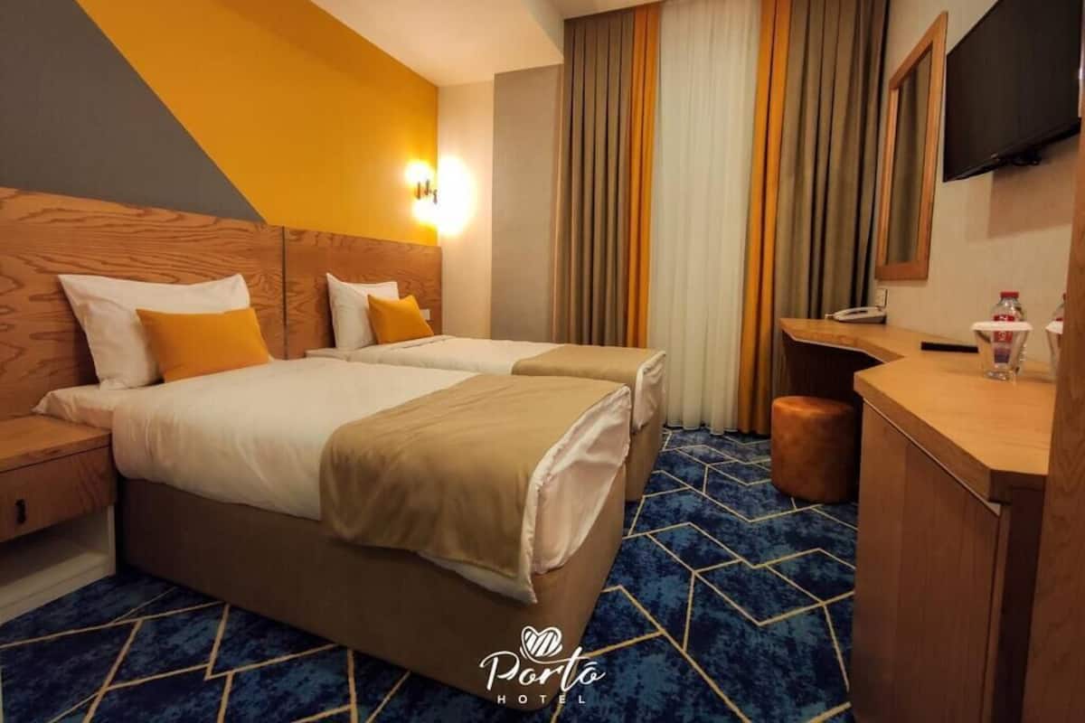 Ein Hotelzimmer mit zwei Betten, einem Schreibtisch, einem Fernseher und einer Minibar.