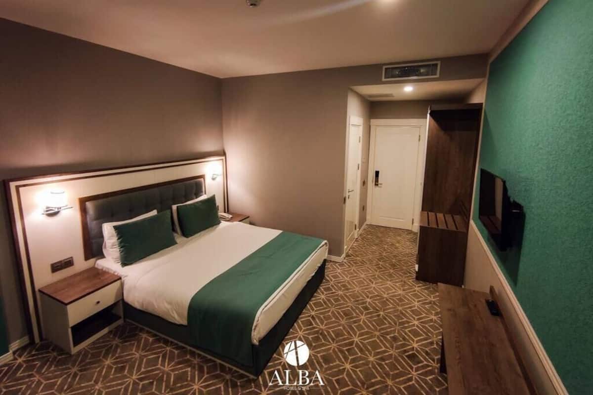 Ein Hotelzimmer mit Bett, Nachttischen, einem Fernseher und einer grünen Wand.