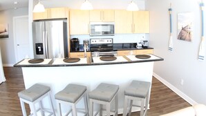 A modern kitchen with a central island, stainless steel appliances, and wooden cabinets.