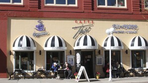 A building with multiple storefronts, including a cappuccino shop, a cafe, and a bakery.