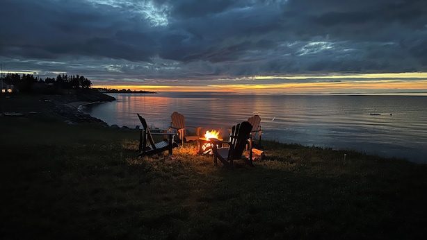A beach scene with chairs and a fire, overlooking a calm sea and a sunset. - Oceanfront beach cottage panoramic views spectacular sunsets sandbars warm water (Pictou)