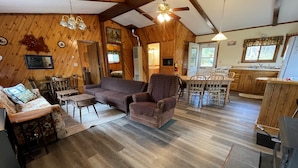 Un intérieur de chalet chaleureux comprenant un salon, un coin repas et une cuisine.