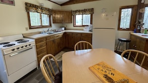 Une cuisine de style rustique, avec des meubles en bois, une cuisinière, un évier et une table à manger agrémentée d’une pancarte de bienvenue.