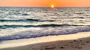A beach with waves and a sunset.