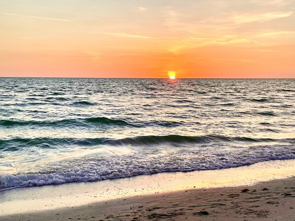 A beach with waves and a sunset.