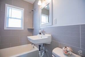 Bañera con ducha, toallas, papel higiénico
