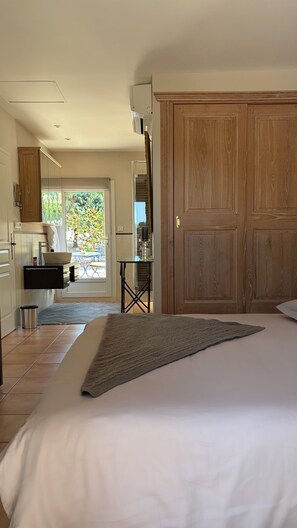 Een slaapkamer met een groot bed, een houten garderobe en uitzicht op een tuin door een raam.