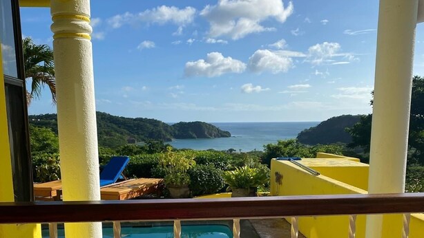 Ein Balkon mit Blick auf einen Pool und das Meer.