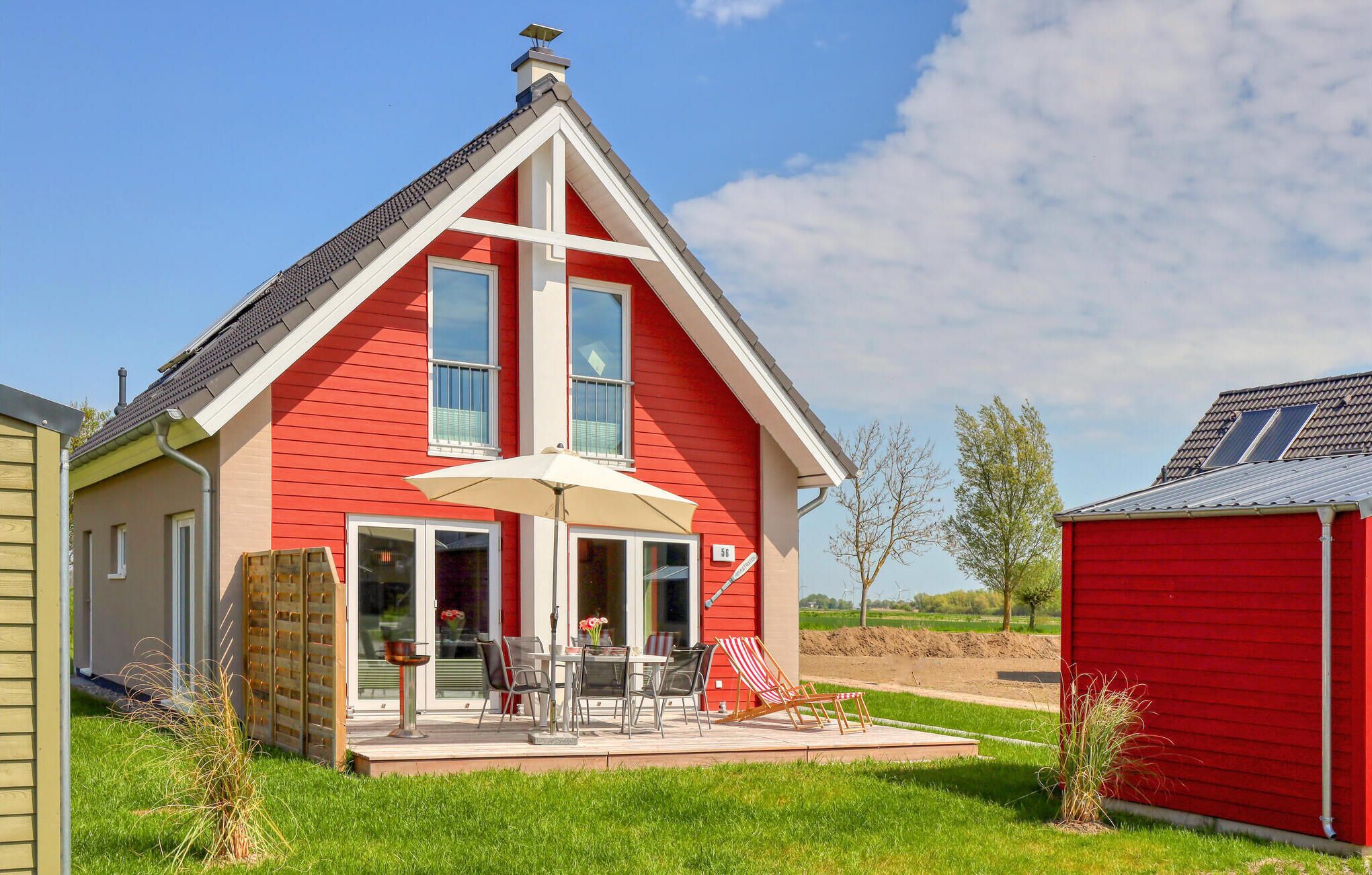 A red house with a patio, a chimney, and a number 56 sign.