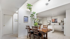A modern kitchen with white cabinets, a central island, and a dining area with a wooden table and chairs. - Family vacation home at Cultus Lake - Pet Friendly (Cultus Lake)