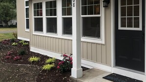 A single-story house with a beige exterior, white trim, and a black front door. - Sparkling Home in Saugatuck area! (Douglas)