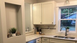 A kitchen with white cabinets, a dishwasher, a sink, and a window with a view of the outside. - Sparkling Home in Saugatuck area! (Douglas)