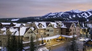 Un hôtel composé de plusieurs bâtiments, dont les toits sont recouverts de neige, et qui est situé dans un cadre montagneux.