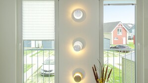 Ett rum med tre infällda vägglampor och utsikt över ett bostadsområde genom ett fönster.