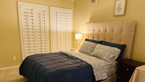 A bedroom with a bed, nightstand, lamp, and two doors. - Momo's cozy  home 2BR/2BA with pool (Dallas)
