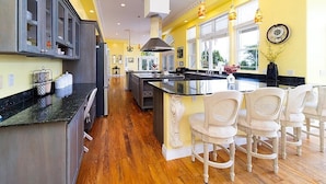 A kitchen with a central island, wooden flooring, and a yellow accent wall. - Hale Hilo Bay Tropical Hideaway (Hilo)