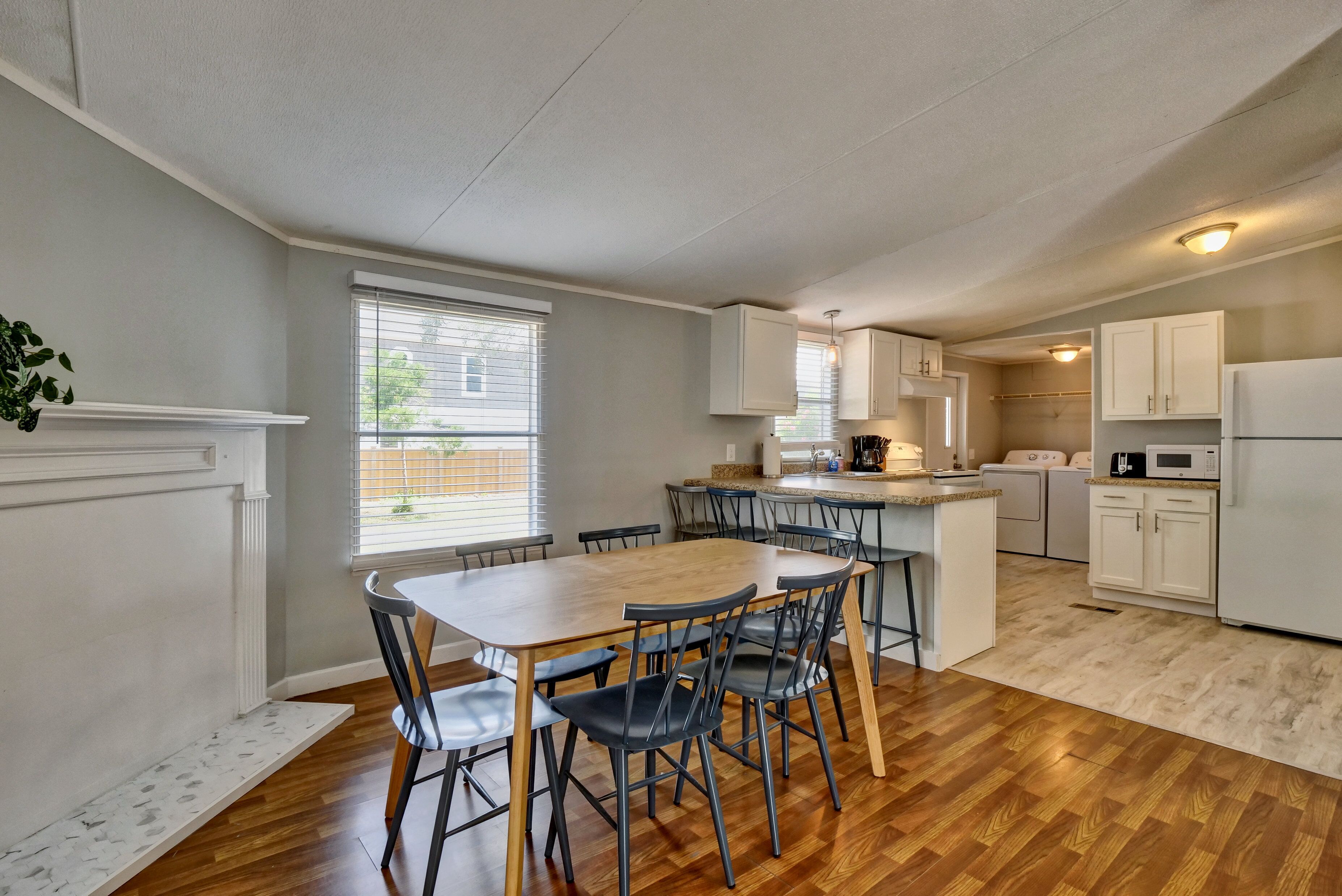 Una cocina moderna con armarios blancos, una mesa de comedor de madera y sillas.
