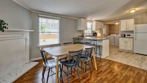 Una cucina moderna con mobili bianchi, un tavolo da pranzo in legno e sedie.