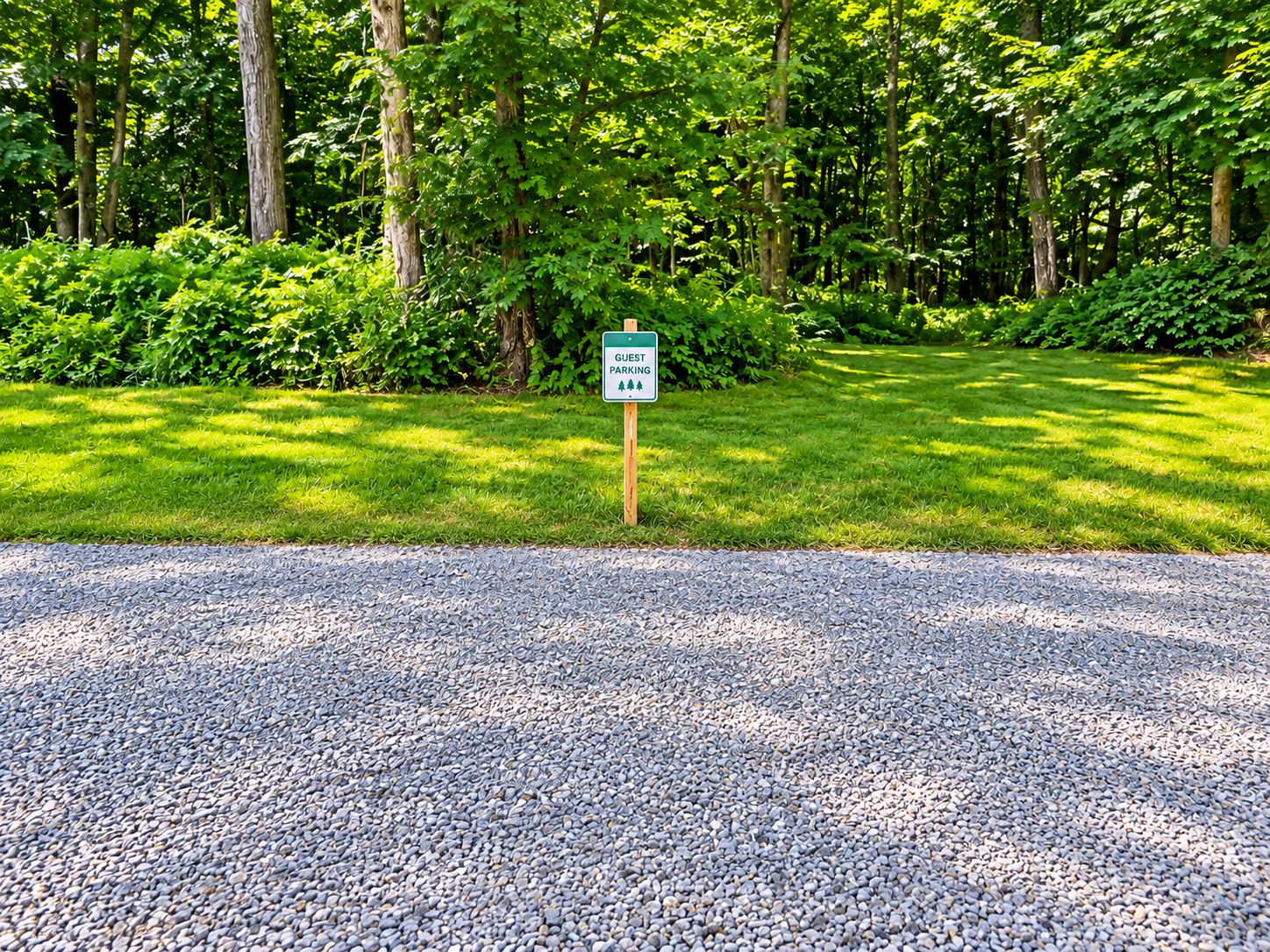 A sign indicating a guest parking area with a gravel path leading to it.