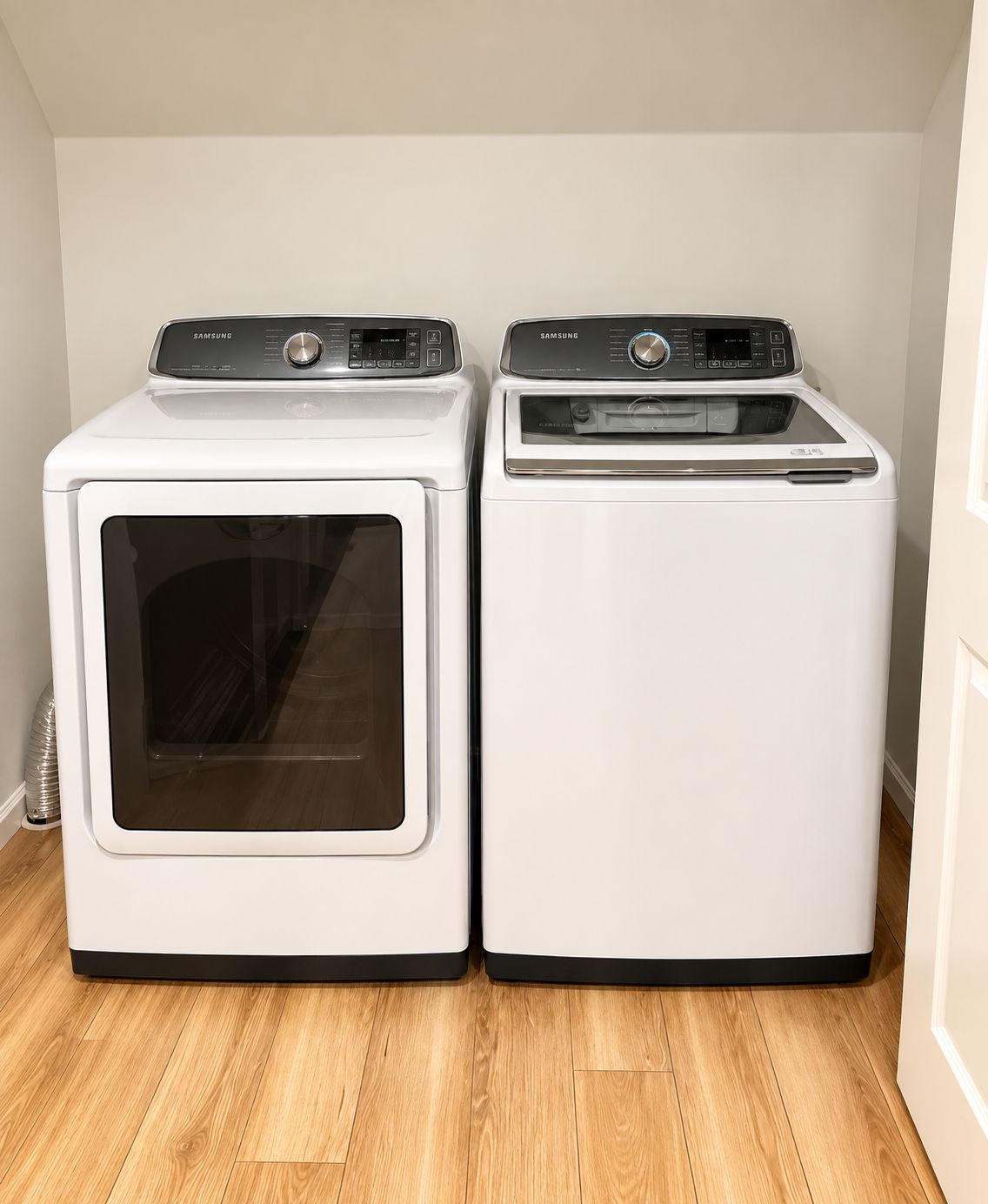 Deux machines à laver Samsung blanches se trouvent dans une pièce dont le sol est en bois et les murs sont blancs.
