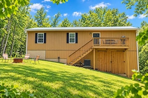 A two-story wooden house with a balcony, a covered porch, and a fire pit area.
