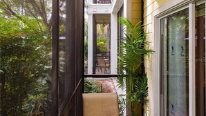 A narrow outdoor corridor with a potted plant, a chair, and a view of a patio area. - Amazing Bahama Bay Resort, close to Disney (Davenport)