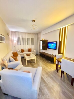 Uma sala de estar moderna com sofá, mesa de centro, televisão e área de jantar.