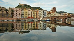 Une ville située au bord de l’eau, avec des bâtiments aux couleurs vives, un pont et des bateaux dont le reflet se mire dans l’eau.