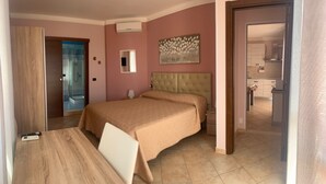 Une chambre à coucher avec un lit, une table de chevet et une vue sur la salle de bain et la cuisine.