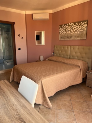 Une chambre dotée d’un grand lit, d’une douche, d’un téléviseur à écran plat et d’un tableau au mur.