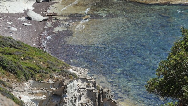 Un paysage côtier caractérisé par des falaises rocheuses et une eau d’un bleu limpide.