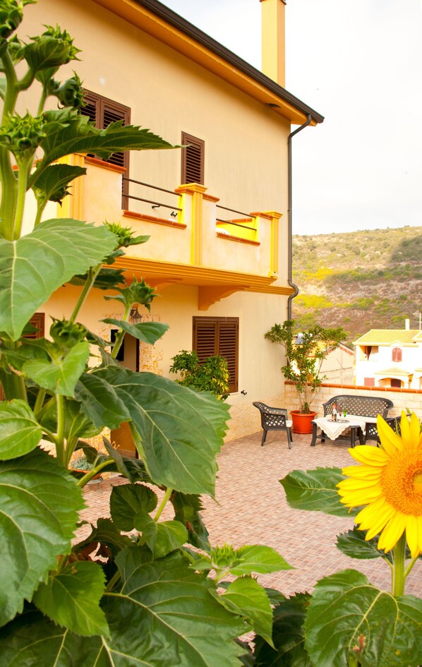 A building with a tiled courtyard, a balcony, and a view of the surrounding landscape.