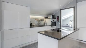 Uma cozinha moderna com armários brancos, uma ilha central e micro-ondas sobre a pia.
