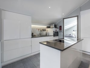 Une cuisine moderne avec des meubles blancs, un îlot central et un four à micro-ondes placé au-dessus de l’évier.