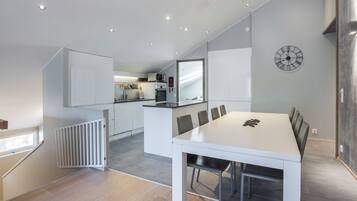 Una cucina moderna con mobili bianchi, un forno a microonde integrato e un'area pranzo con tavolo e sedie bianche.