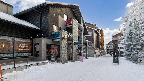 A snow-covered street with buildings, including a restaurant with a visible sign.